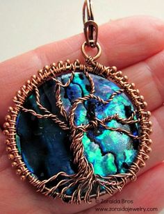 a tree of life pendant is shown in the hand