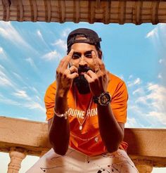 a man sitting on top of a wooden bench with his hands covering his face while holding a cell phone up to his mouth