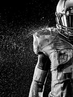 a black and white photo of a football player wearing a uniform covered in water droplets