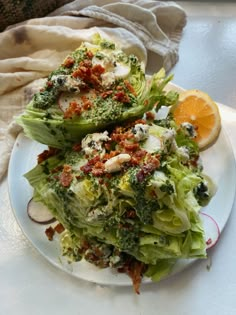 a white plate topped with lettuce covered in dressing next to an orange slice