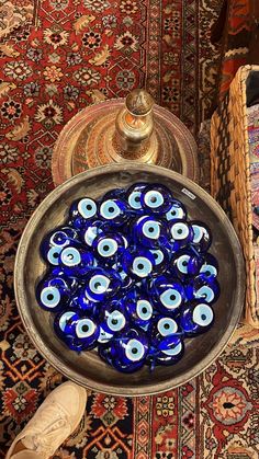 blue glass eyeballs in a silver bowl on a table next to a lamp and rug