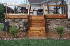 a wooden deck with stairs leading up to the top floor and an outdoor grill area