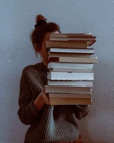 a woman holding a stack of books in front of her face