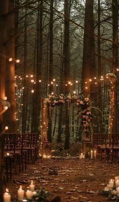 an outdoor wedding setup with candles and flowers on the ground, surrounded by tall trees