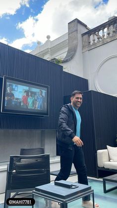 a man in a blue shirt and black pants is walking through a room with chairs