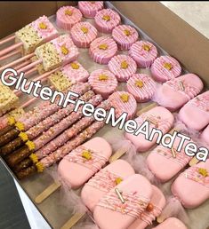 a box filled with lots of pink and yellow decorated cookies next to marshmallows