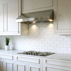 a stove top oven sitting inside of a kitchen next to white cupboards and drawers