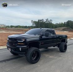 a large black truck parked on the side of a road next to a construction site