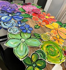 a table with flowers painted on it in different colors and shapes, sitting next to a door