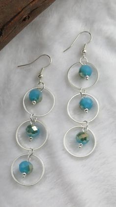 three circles with blue beads hanging from them on a white furnishing background,