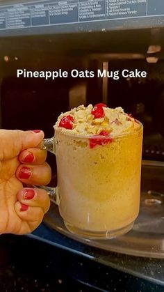 a person holding a cup with some food in it and the words pineapple oats mug cake