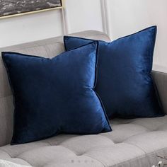 two blue pillows sitting on top of a couch