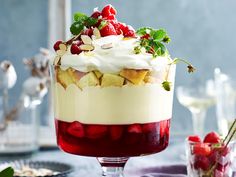 a trifle with strawberries and whipped cream in a glass dish on a table