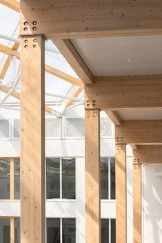 the inside of a building with wooden beams and glass walls on both sides, in front of several windows