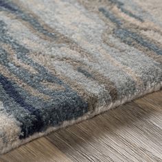 a close up view of a rug on the floor with wood floors and grey carpeting