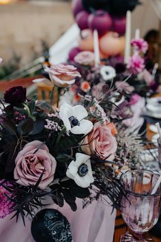 an arrangement of flowers and candles on a table