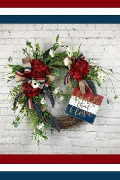 two wreaths with flowers on them are hanging against a brick wall, one is red and the other is blue