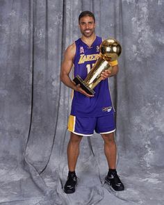 a man holding a trophy in his right hand and wearing a purple uniform with gold trim