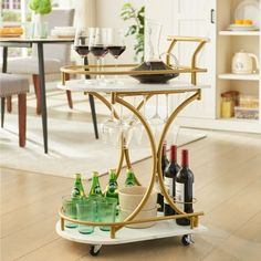 a gold bar cart with wine glasses and bottles on the bottom shelf in front of a dining room table