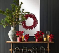 a christmas mantle with candles, wreath and poinsettis on it in front of a mirror