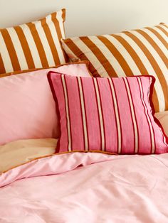 a bed with pink and brown striped pillows