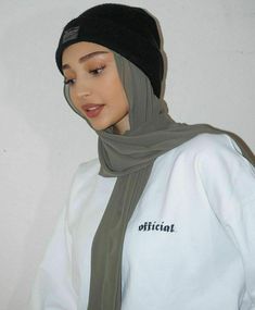 a woman wearing a white sweatshirt with a black beanie on top of her head