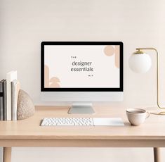 a desktop computer sitting on top of a wooden desk next to a book and lamp