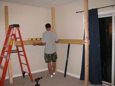 a man standing on top of a ladder in a room