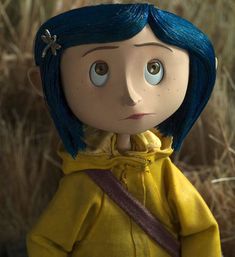 a doll with blue hair wearing a yellow jacket