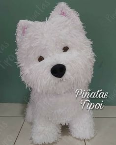 a white stuffed dog sitting on top of a tile floor next to a green wall