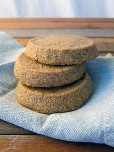 three cookies stacked on top of each other on a blue napkin next to a wooden table