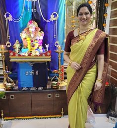 a woman in a yellow and brown sari standing next to an idol on display