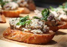 bread with meat and herbs on it sitting on a cutting board