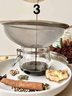 coffee being poured into a glass cup on top of a plate with spices and nuts