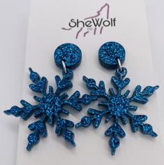 two blue snowflake earrings on top of a piece of paper with the word showoff