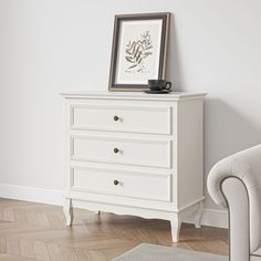 a white dresser sitting next to a chair in a room