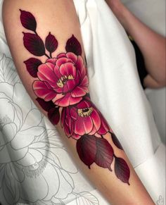 a woman's arm with flowers and leaves on it