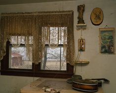 a room with a guitar and other items on the table in front of a window