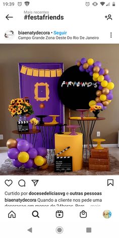 the table is set up with purple and yellow balloons, black sign, and other decorations