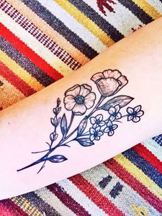 a woman's arm with flowers on it and the word love written in black ink