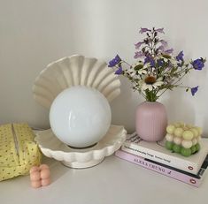 there is a vase with flowers in it next to some books and an egg shell