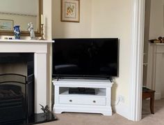 a flat screen tv sitting on top of a white entertainment center next to a fire place