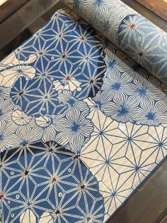 two rolls of blue and white fabric sitting on top of a wooden table next to each other