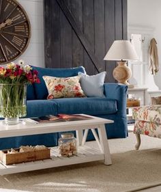 a living room with blue couches and flowers in vases on the coffee table