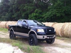 a black truck parked in front of some hay bales