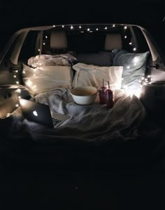 an open car trunk filled with pillows and food on it's side, surrounded by lights