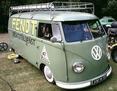 an old vw bus is parked in the grass with other vehicles behind it,