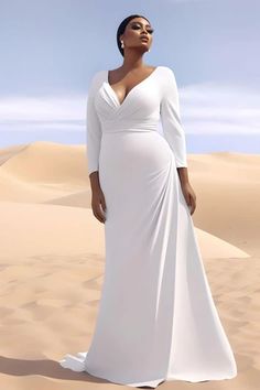 a woman standing in the desert wearing a white dress