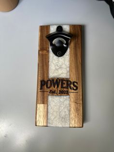 a wooden board with a black bottle opener on it and some white wool in the bottom