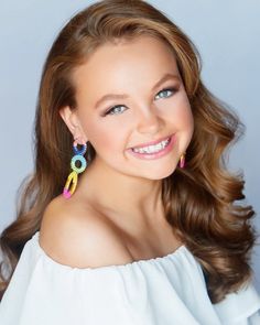 a woman with long brown hair wearing colorful earrings